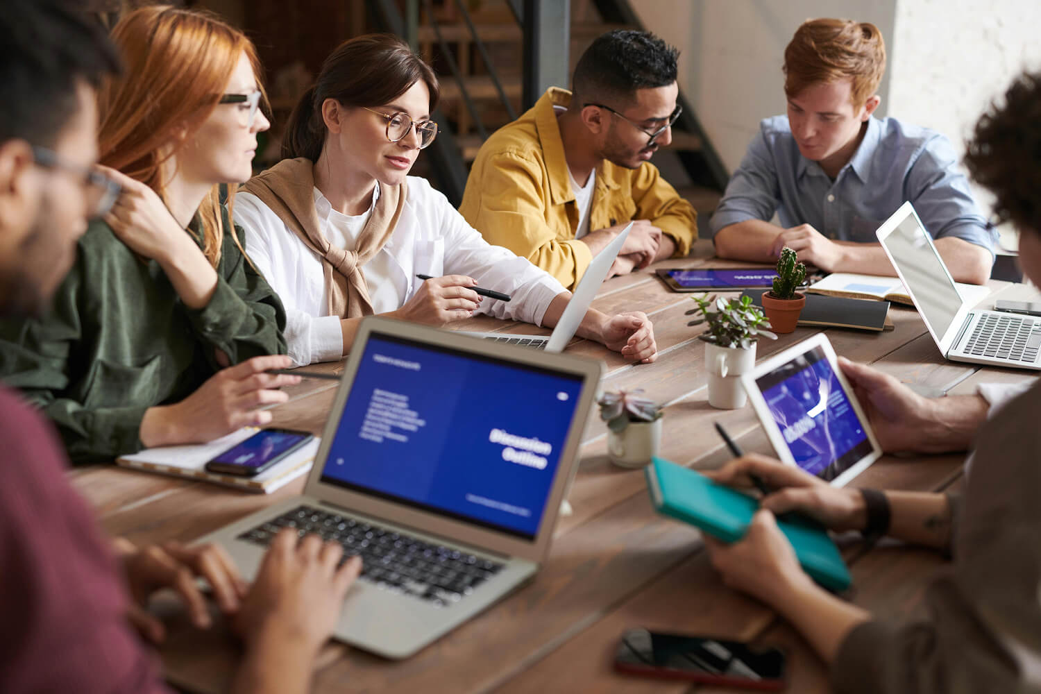 A team of people sat around a conference table with their laptops